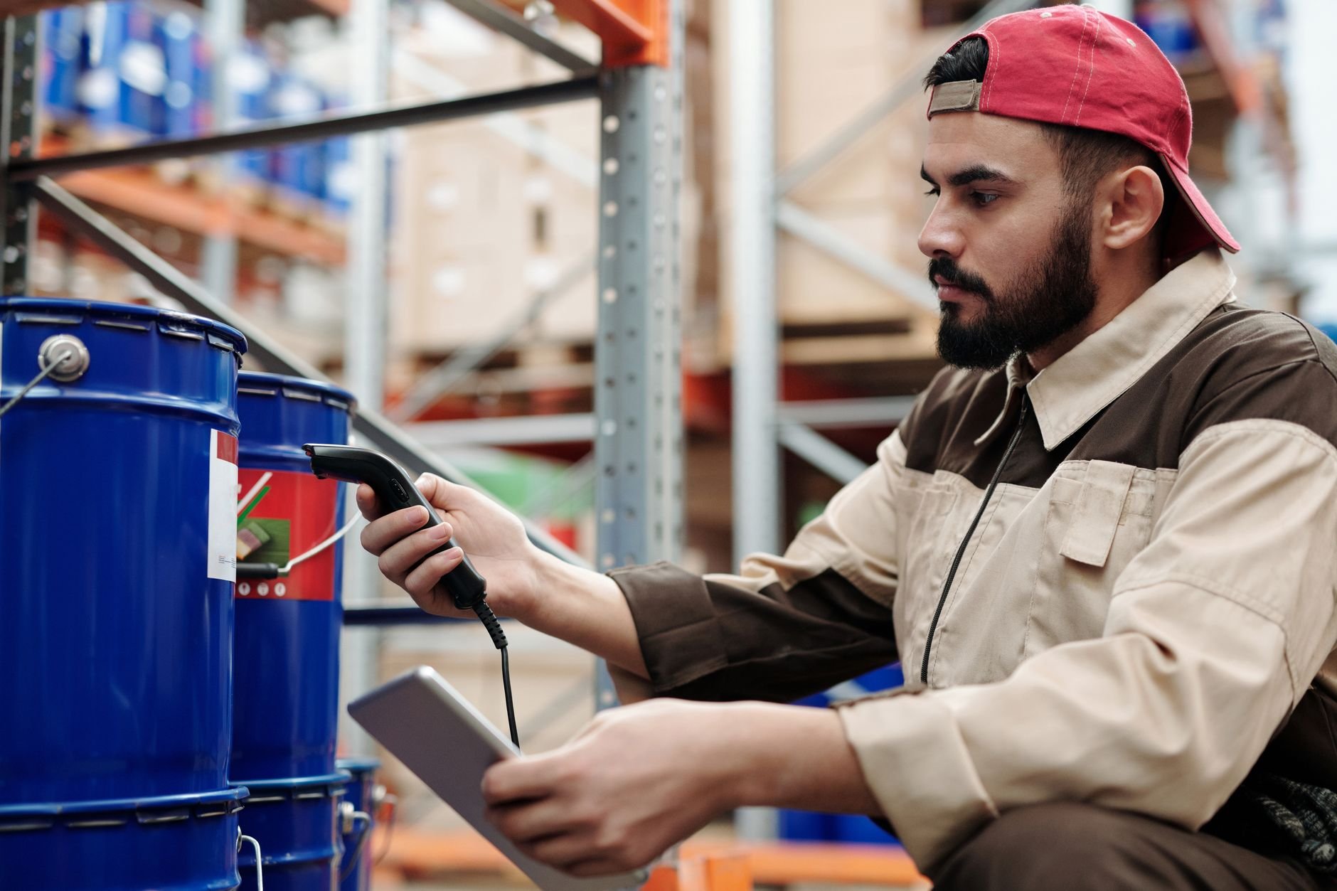 Male warehouse worker scanning barrels with a tablet for inventory management